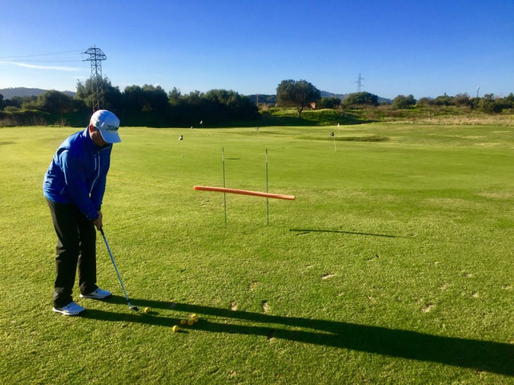 Ein Ball unten durch und ein Ball oben durch – Ziel zur Fahne. Die Poolnudel wird bei jedem Durchgang etwas verschoben, ohne dass der Golfer das sieht.